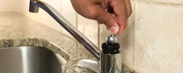 Hand replacing a cartridge in a kitchen faucet at a stainless steel sink