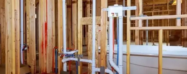 Wall framing with new white drain and vent pipes in a bathroom rough-in